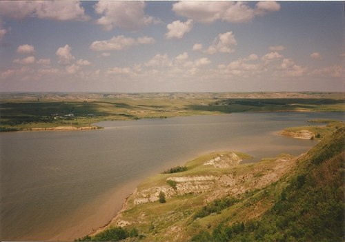 A scenic view of a river winding through green hills under a partly cloudy sky.