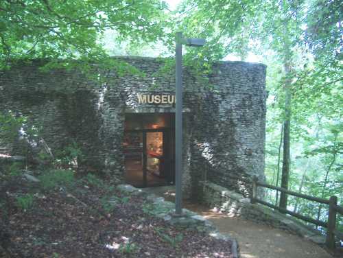 Entrance to a stone museum surrounded by lush greenery and trees.