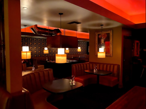 Cozy restaurant interior with red lighting, leather booths, and stylish pendant lamps.