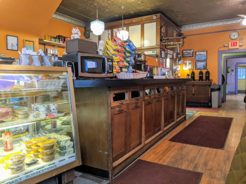 A cozy café interior featuring a wooden counter, snack display, and colorful decor with warm lighting.