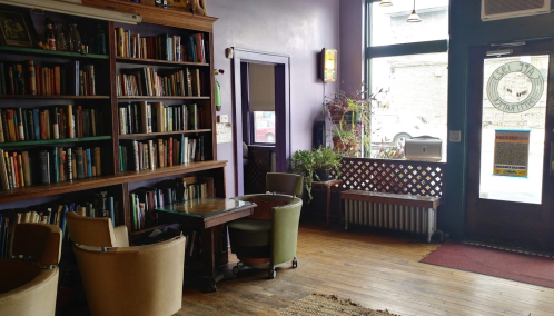Cozy interior of a café with bookshelves, seating, and a welcoming entrance.