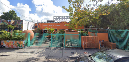 Colorful restaurant exterior with a sign reading "CRAMPS," featuring outdoor seating and lush greenery.