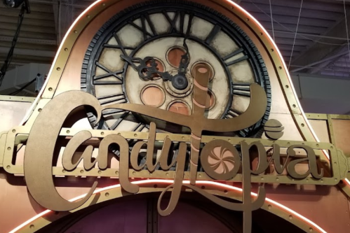 Sign for "Candytopia" featuring a decorative clock and whimsical lettering.