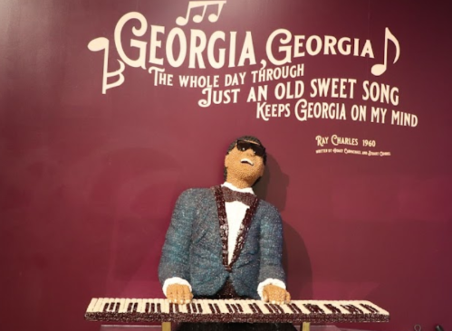 A sculpture of a musician in a suit playing a keyboard, with lyrics from "Georgia on My Mind" on the wall behind.