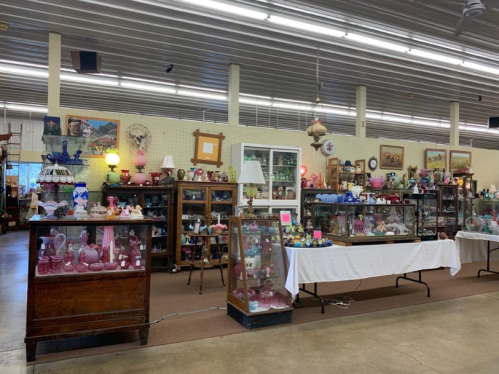 A vintage shop interior filled with glass displays showcasing colorful collectibles and decorative items.