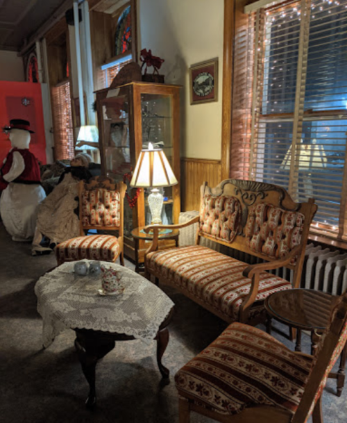 Cozy vintage sitting area with patterned furniture, a lamp, and decorative items in a warmly lit room.