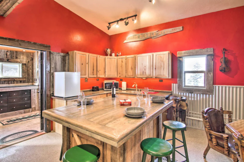 Cozy kitchen with red walls, wooden cabinets, a large island, and rustic decor, featuring a violin and a wine bottle.