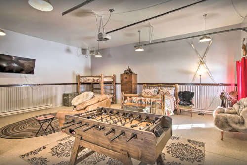 A cozy game room featuring a foosball table, seating area, bunk beds, and rustic decor.