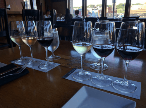 A table set with various wine glasses, showcasing different types of wine, with a scenic view in the background.