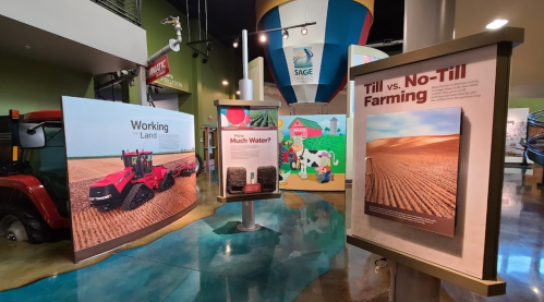 Exhibits on farming techniques and water usage in an agricultural museum, featuring a tractor and colorful graphics.
