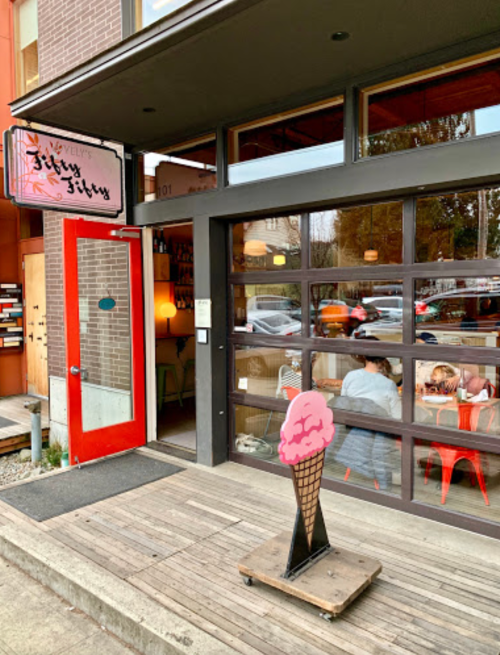 Exterior of a colorful ice cream shop with a red door and a sign reading "Fifty Fifty," featuring a cone sign out front.