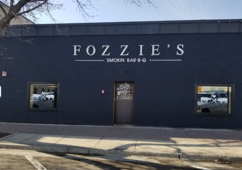 Exterior of Fozzie's Smokin Bar-B-Q, featuring a dark blue facade and large windows.