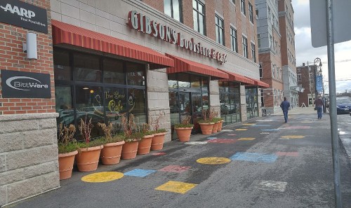 A bookstore and café with colorful painted circles on the sidewalk, surrounded by large planters.