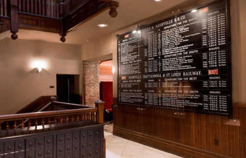 Historic train schedule board displayed in a vintage railway station, featuring destinations and departure times.