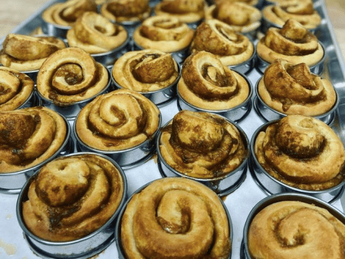 A tray of freshly baked cinnamon rolls in metal baking cups, showcasing their golden-brown swirls.