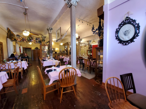 Cozy restaurant interior with pink tablecloths, wooden chairs, and decorative elements on the walls and ceiling.