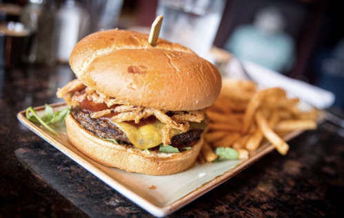A juicy cheeseburger topped with crispy onions on a plate, accompanied by a side of golden French fries.