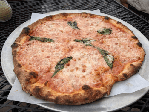 A freshly baked pizza with a golden crust, topped with tomato sauce, melted cheese, and fresh basil leaves.