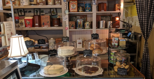 A cozy display of assorted baked goods under glass domes in a charming shop, with vintage decor in the background.