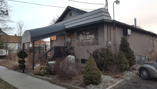 Exterior of the Oak Tree Lodge, featuring a sloped roof, entrance awning, and landscaped surroundings.