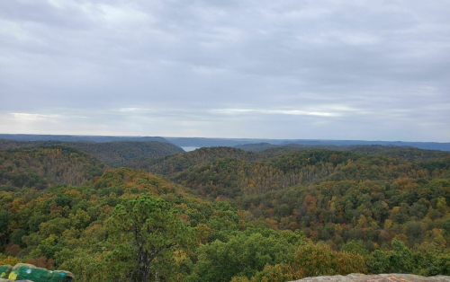 A panoramic view of rolling hills covered in autumn foliage under a cloudy sky.