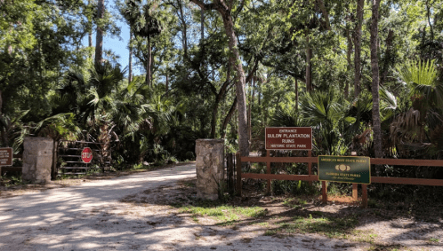 Entrance to Bledsoe Plantation Ruins, featuring a stop sign and signs for the historic state park, surrounded by trees.