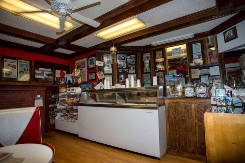 A cozy diner interior featuring a display case, wooden paneling, and vintage decor on the walls.