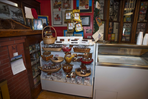 Display of decorative bowls and baskets on a shelf in a cozy shop, with memorabilia and a counter in the background.
