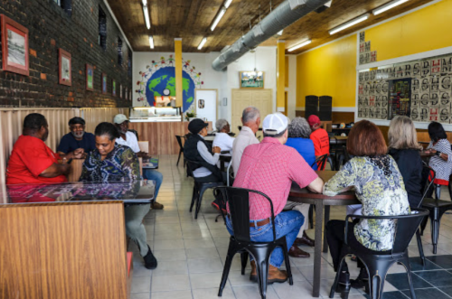 A diverse group of people socializing in a cozy café with colorful decor and a warm atmosphere.