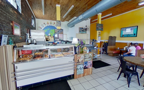 A cozy café interior with a display case, colorful walls, and customers enjoying their meals at tables.