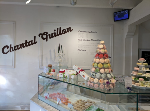 Display of colorful macarons in a pastry shop with the name "Chantal Guillon" on the wall.