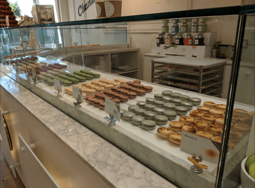A display case filled with colorful macarons and pastries in a bakery.