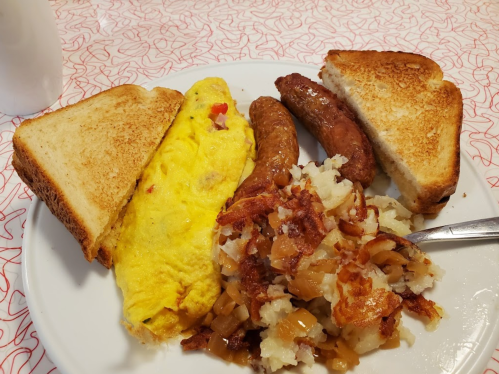 A plate of breakfast featuring an omelet, sausage links, hash browns, and toasted bread.