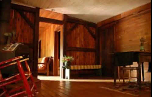 Cozy interior of a wooden room featuring a rocking chair, a table, and warm lighting.
