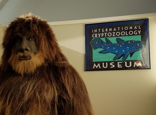 A life-sized Bigfoot figure stands next to a sign for the International Cryptozoology Museum.