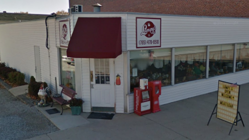 Exterior of a small store with a red awning, large windows, and a sign welcoming customers.