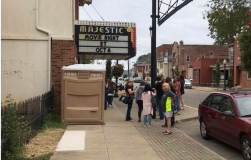 A group of people gathers outside the Majestic theater for movie night, with a marquee displaying the event details.