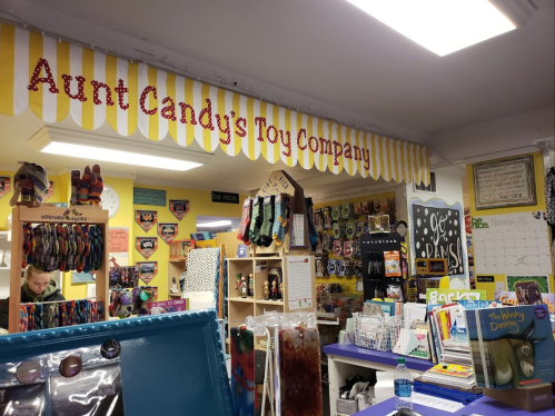 Interior of Aunt Candy's Toy Company, featuring colorful displays of toys and games under a striped banner.