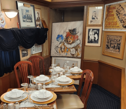 A cozy dining area with a circus-themed clown painting and vintage circus posters on the walls.