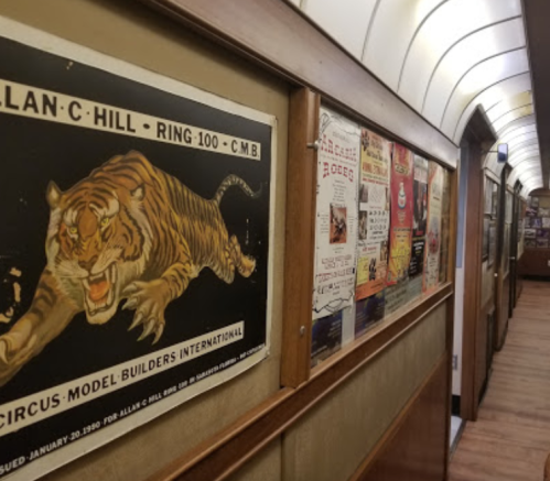 A hallway displaying vintage circus posters, including a fierce tiger illustration, along the walls.