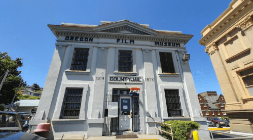 Exterior of the Oregon Film Museum, a historic building with "County Jail" signage, under a clear blue sky.