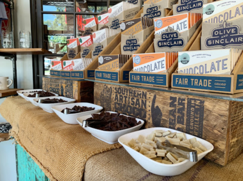 A display of chocolate bars and samples in bowls, set on a rustic wooden counter with burlap.