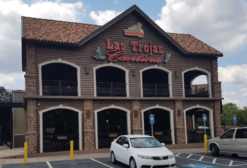 Exterior of Las Trojas Cantina, a two-story restaurant with a rustic design and outdoor seating.