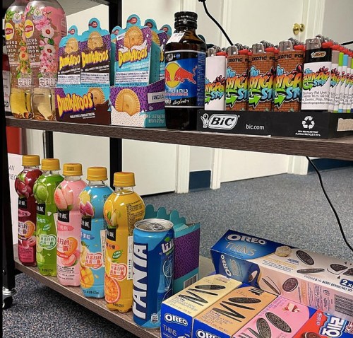 A shelf displaying various snacks and drinks, including candies, sodas, and Oreo cookies.