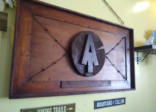 Wooden wall art featuring a stylized "LA" logo, framed with decorative elements and surrounded by hiking trail signs.