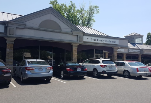 Exterior of M-Learn Family Restaurant with parked cars in front and a clear blue sky.