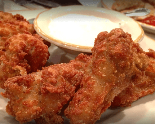 Crispy fried chicken wings served with a side of dipping sauce.