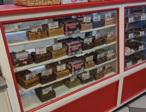 A display case filled with various types of homemade fudge, labeled with different flavors.