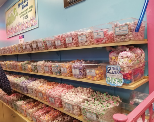 A colorful display of assorted candies in jars on shelves, with a sign for 2-pound bags priced at $17.88.