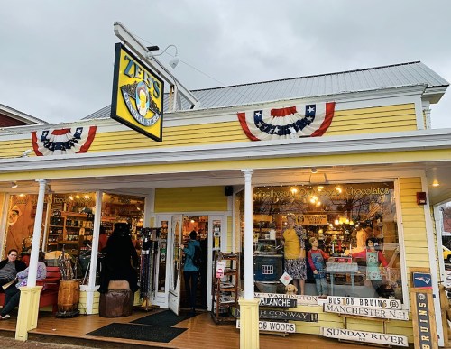 A colorful storefront with a yellow exterior, featuring a sign for "Zeb's General Store" and festive decorations.